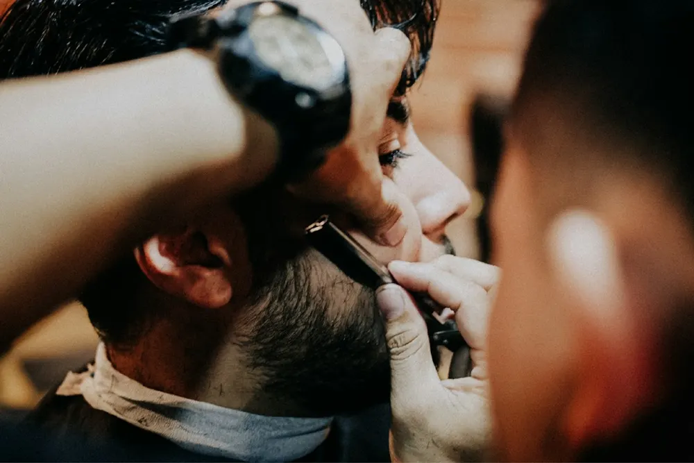 Barber giving a client a straight razor shave